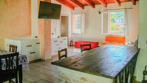 Un comedor con mesa y sillas de madera, un banco rojo y una cocina con encimera y armarios blancos.