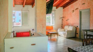 Una habitación con techo de madera, una bañera blanca, un sofá color beige y una mesa de comedor.