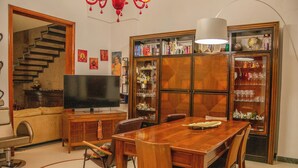 Ein Essbereich mit einem Holztisch und Stühlen, einem Fernseher und einer Bücherwand voller Bücher und Dekoration.
