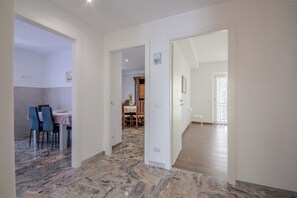 A spacious room with a marble floor, a dining area with a table and chairs, and a view of a kitchen area. - Magnolia House - Appartamento 1 (Fonte Nuova)