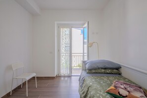 A bedroom with a bed, a chair, and a balcony door. - Magnolia House - Appartamento 1 (Fonte Nuova)