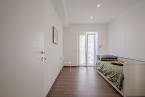 A bedroom with a bed, a chair, a door, and a window. - Magnolia House - Appartamento 1 (Fonte Nuova)