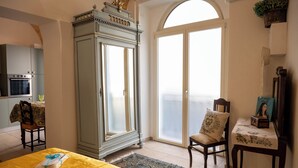 Una habitación con cama, mesa de comedor, armario, silla y un ventanal grande.