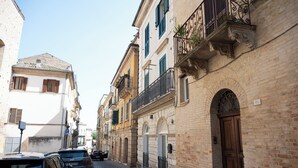 Una estrecha calle adoquinada bordeada de edificios históricos, con balcones de reja y fachada de ladrillo.