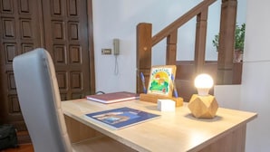 Un escritorio de madera con una silla, un cuadro enmarcado, un libro y una lámpara de escritorio.