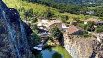 A rural village with traditional stone buildings, a small pond, and a steep cliff.