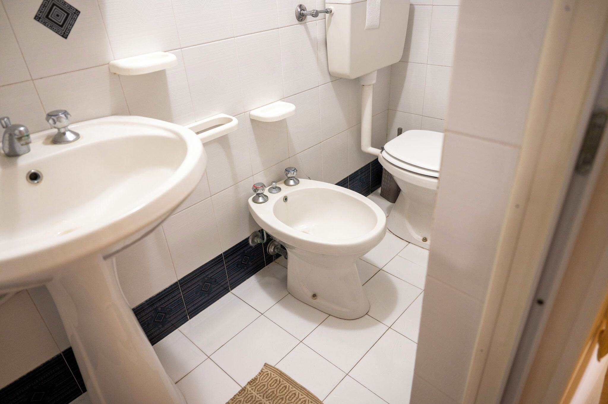 A bathroom with a white sink, a bidet, and a toilet.