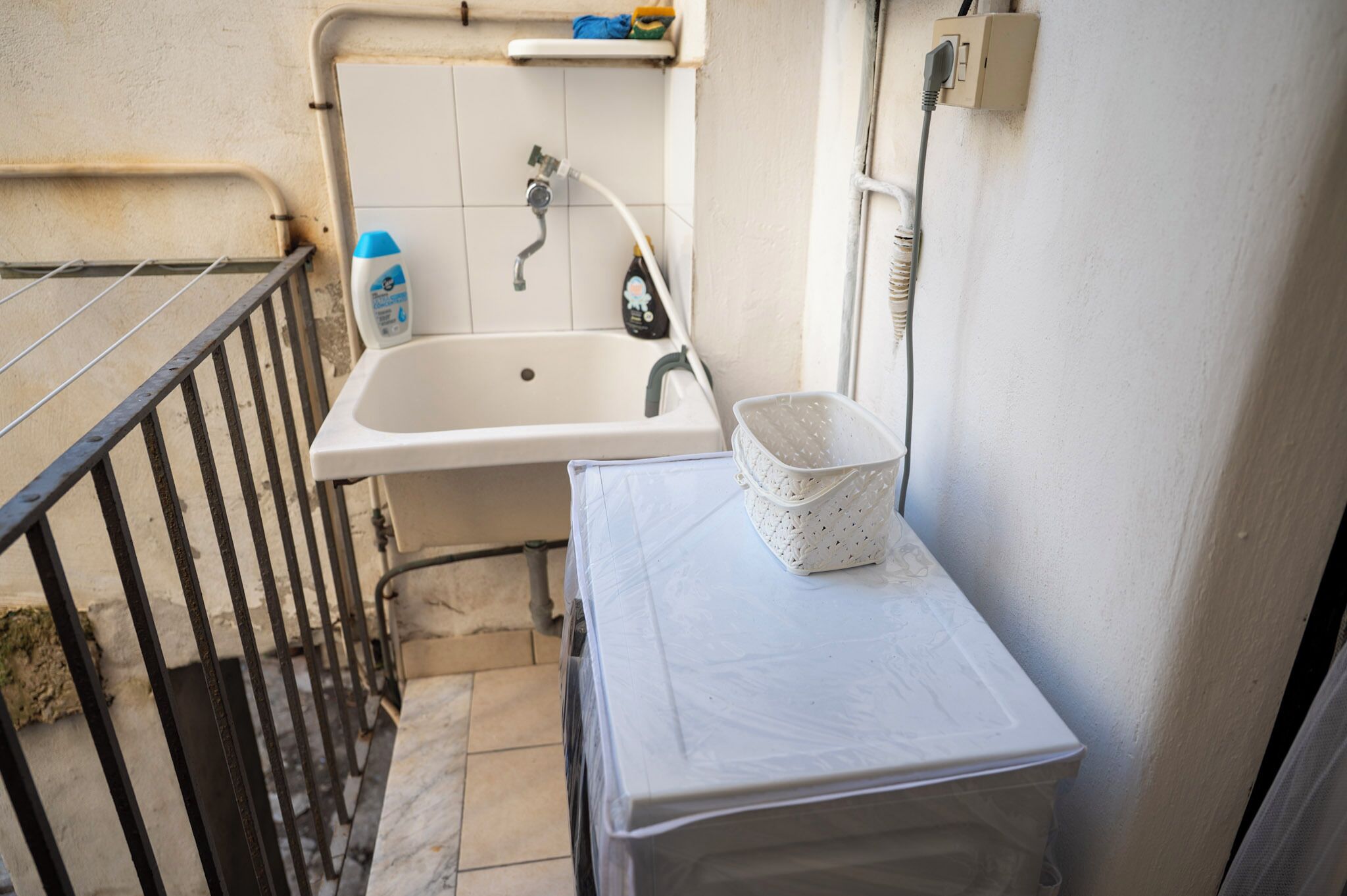 A small bathroom with a white sink, a shower, and a tiled wall.