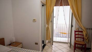Una camera da letto con un letto, un comodino, una sedia e una finestra con tende.