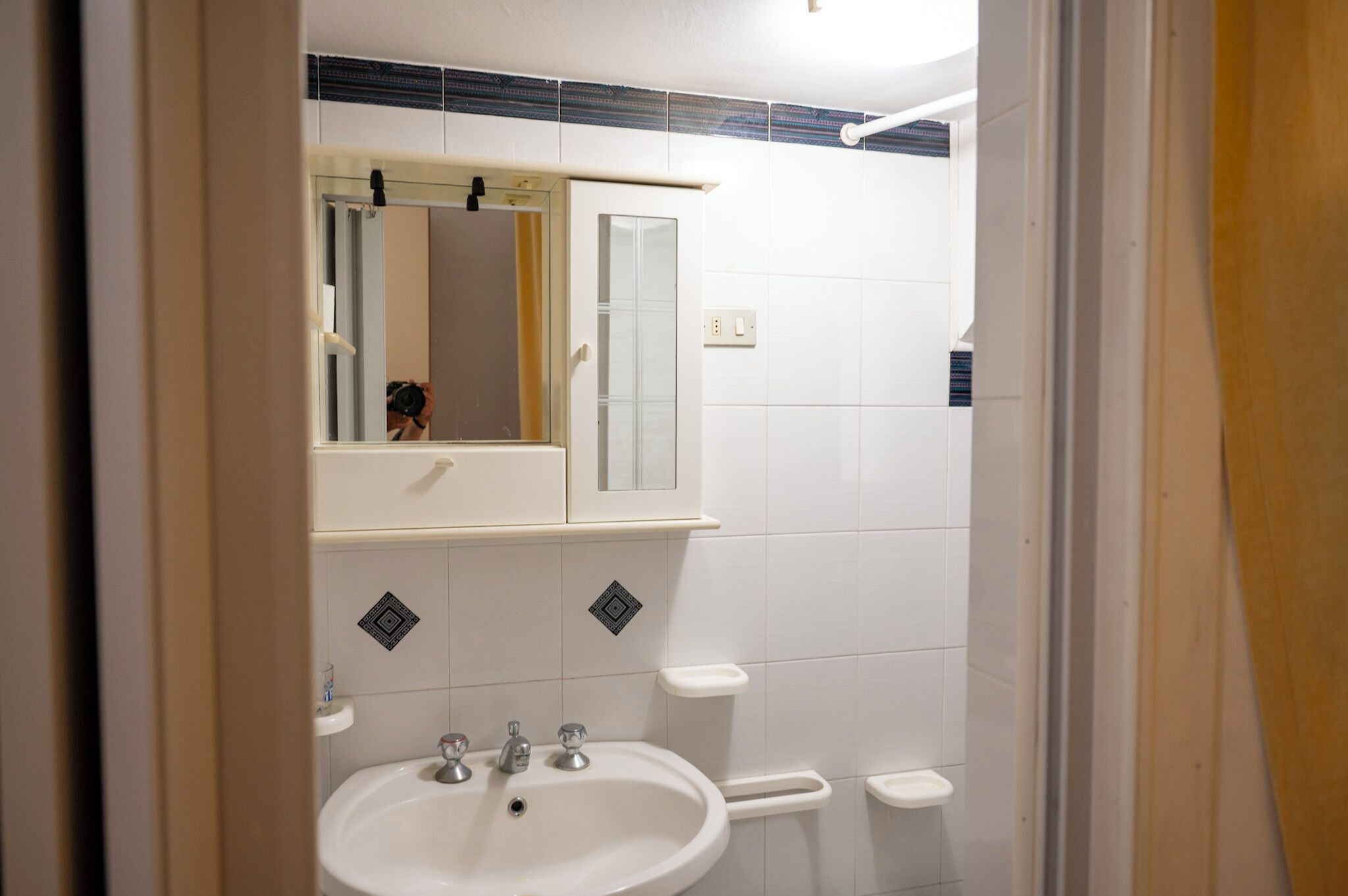 A bathroom with a sink, mirror, and a towel rack.