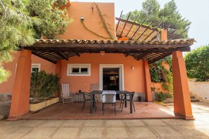 A covered patio area with a table and chairs, surrounded by potted plants and a pergola. - Villa Villacolle (Marsala)