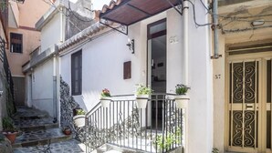 A white building with a stone staircase, a metal railing, and potted plants on the balcony. - Casa In Montagna Vicino Al Mare (Itala)