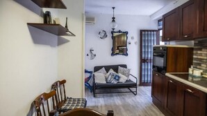 A compact kitchen with wooden cabinets, a dining area with a wooden table and chairs, and a sofa with cushions. - Casa In Montagna Vicino Al Mare (Itala)