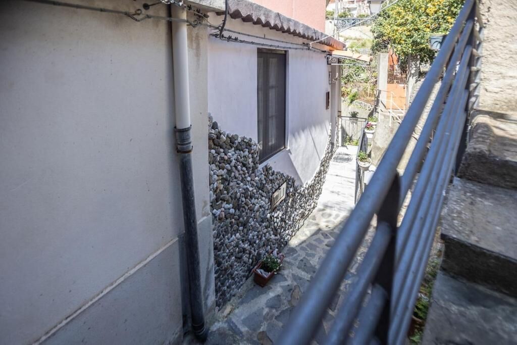 Uma passagem estreita com um edifício de um lado e um corrimão de metal do outro.