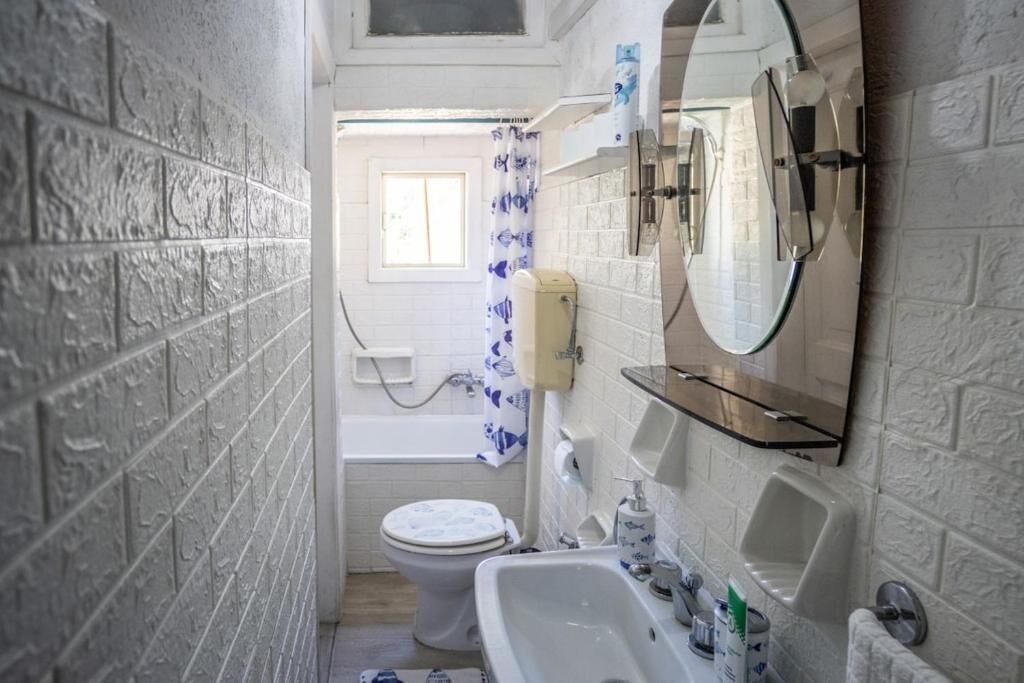 Ein schmales Badezimmer mit Toilette, Waschbecken und Badewanne.