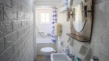 Ein schmales Badezimmer mit Toilette, Waschbecken und Badewanne.