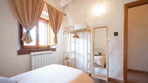 Une chambre à coucher avec un lit, un radiateur, une armoire et un miroir.