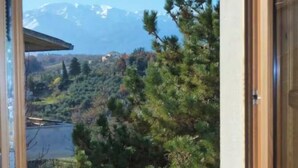 Una habitación con un ventanal grande que ofrece vistas a un paisaje montañoso y una masa de agua.