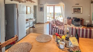 Una cocina amplia con vigas de madera, un refrigerador y un comedor con una mesa preparada para dos.