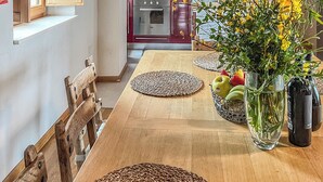 Un comedor con una mesa de madera, individuales tejidos y un jarrón con flores amarillas.