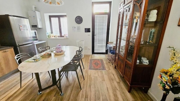 Una cocina con una mesa de comedor, sillas, un refrigerador y un armario.