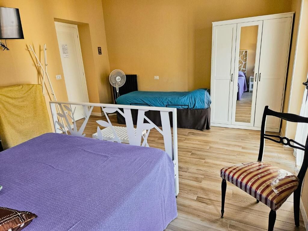 Una habitación con cama, una silla, armario y ventilador.