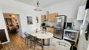Una cocina moderna con comedor, armarios de madera, refrigerador de acero inoxidable y una mesa blanca con sillas.