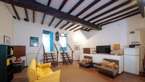 A living room with a yellow sofa, a brown sofa, a TV, a lamp, and a refrigerator. - Il Tasso (Vallerano)