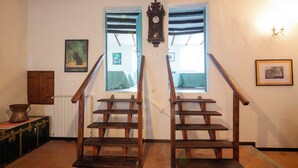 A staircase with wooden steps and a wooden handrail, leading to a landing with two windows. - Il Tasso (Vallerano)