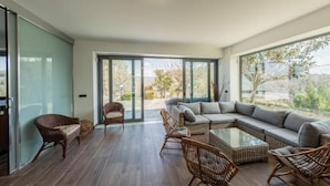A modern living room with a large sectional sofa, wicker chairs, and a glass coffee table. - Villa Petrara - Villa Con Piscina E Spa (San Mango sul Calore)