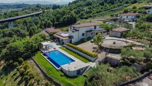 A large house with a swimming pool, surrounded by lush greenery and a bridge in the background. - Villa Petrara - Villa Con Piscina E Spa (San Mango sul Calore)