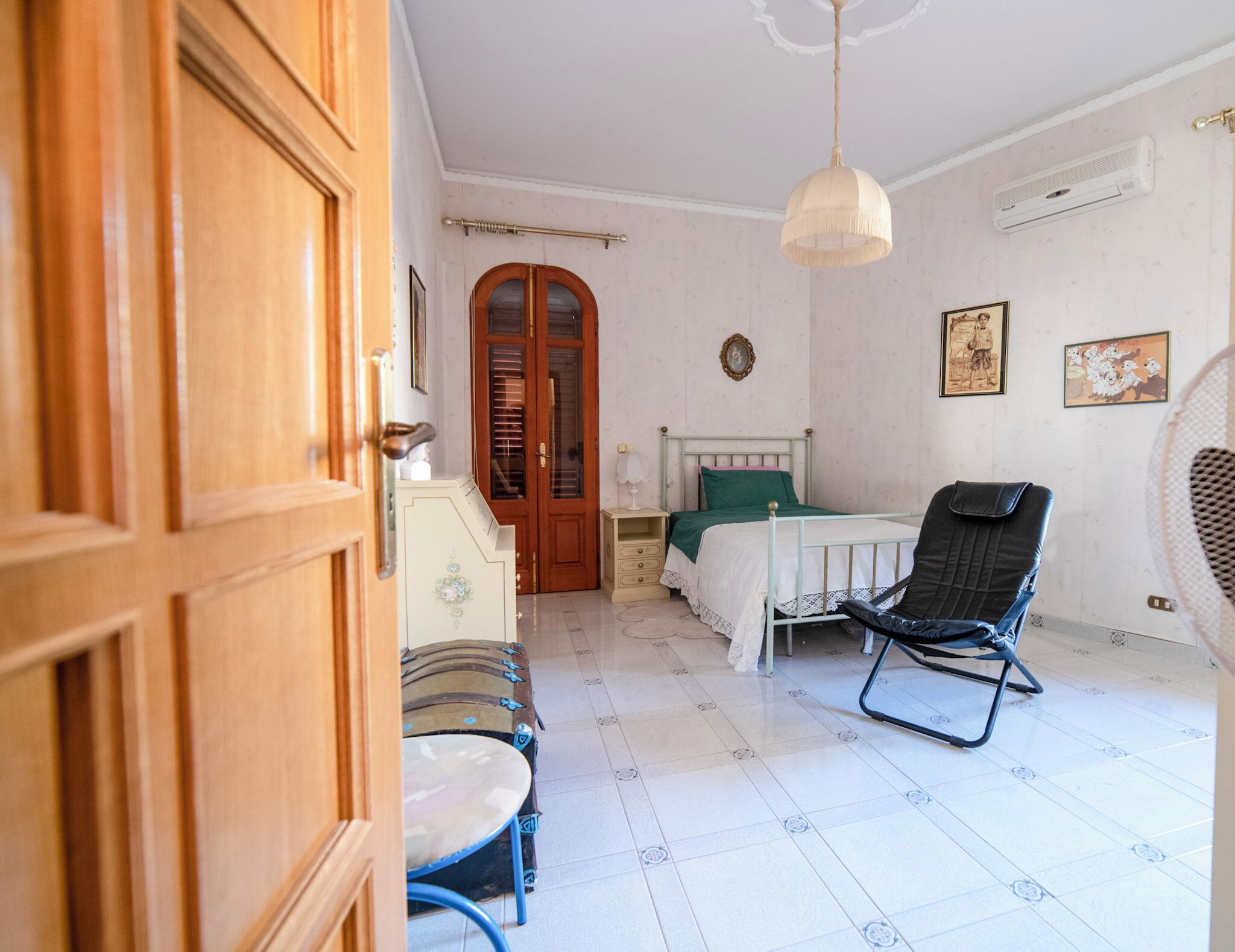 A room with a bed, a chair, a table, a wardrobe, and a door.