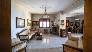 A spacious living room with a fireplace, multiple sofas, and a dining area. - Il Rifugio Del Templare (Roccavaldina)