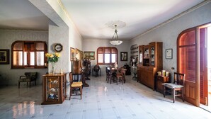 A spacious room with a dining area, wooden cabinets, and a large arched doorway. - Il Rifugio Del Templare (Roccavaldina)