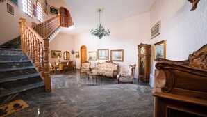 A grand room with a marble staircase, a chandelier, and classic furniture. - Il Rifugio Del Templare (Roccavaldina)