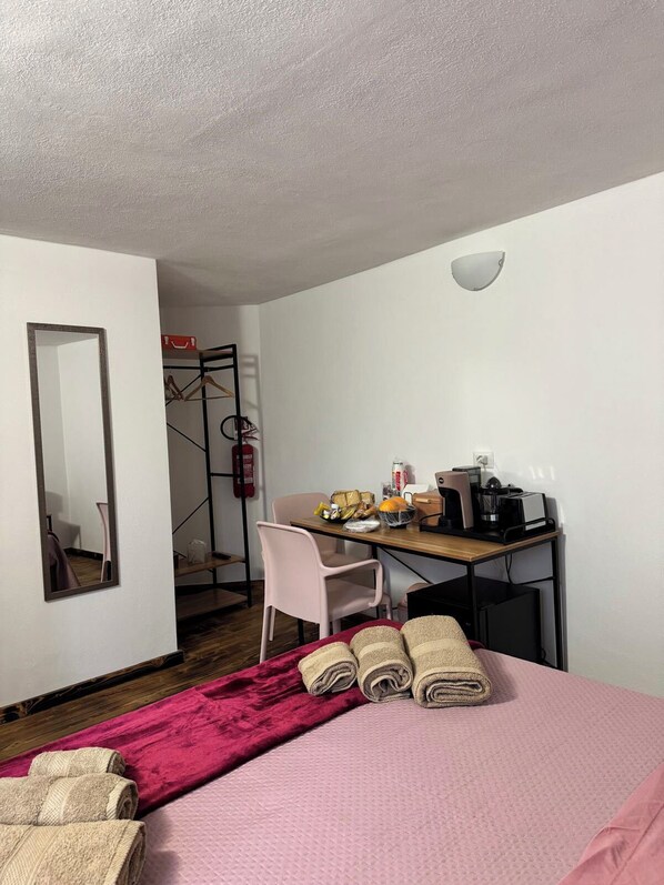 A hotel room with a bed, a desk with a chair, a mirror, and a small kitchenette. - B&B Nonna Cristina (Nardodipace)