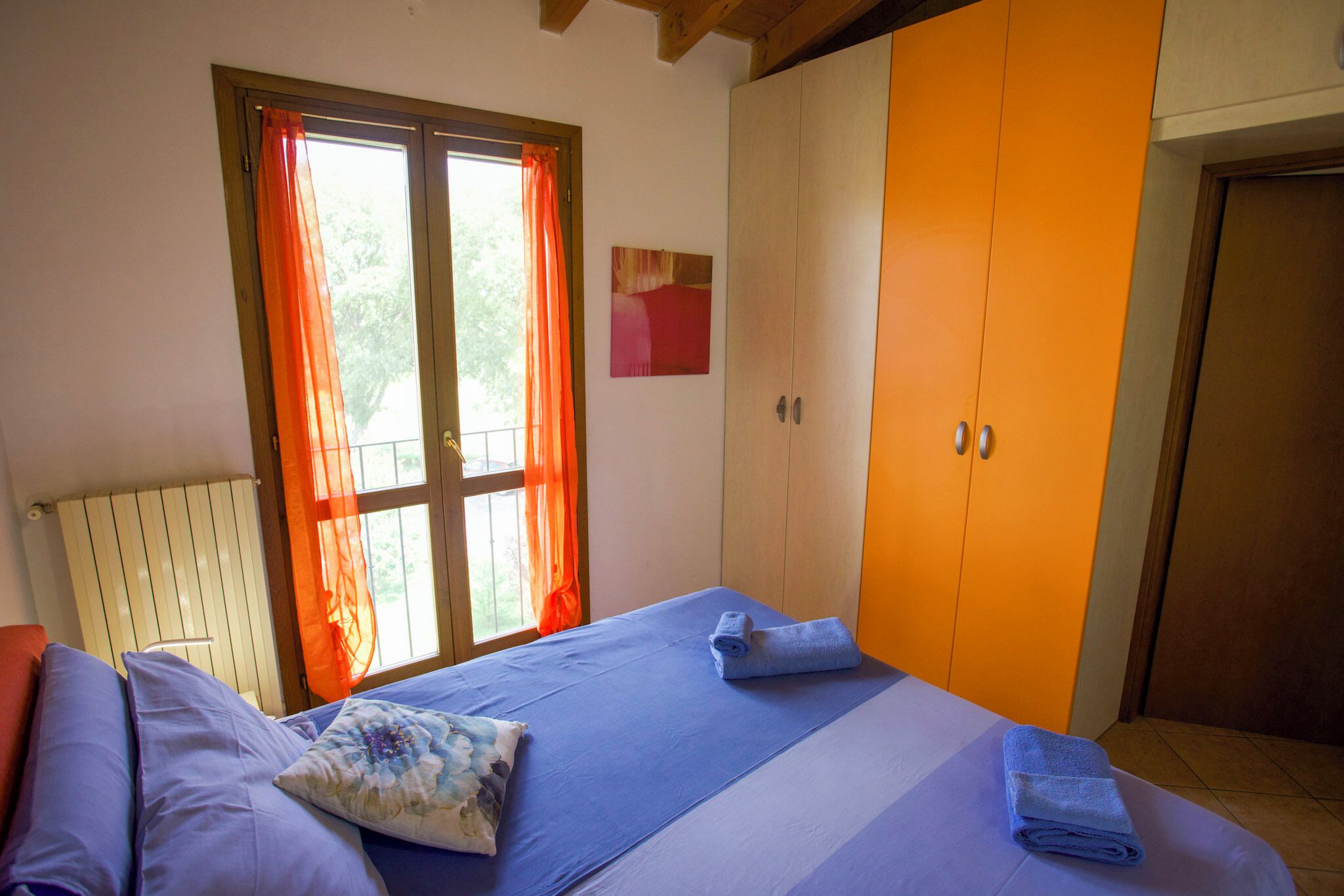 A bedroom with a bed, a wardrobe, and a window with curtains.