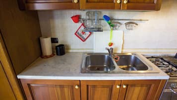 A kitchen with wooden cabinets, a stainless steel sink, and a marble countertop.