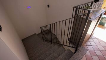 A staircase with a metal railing, a potted plant on the landing, and a tiled floor.