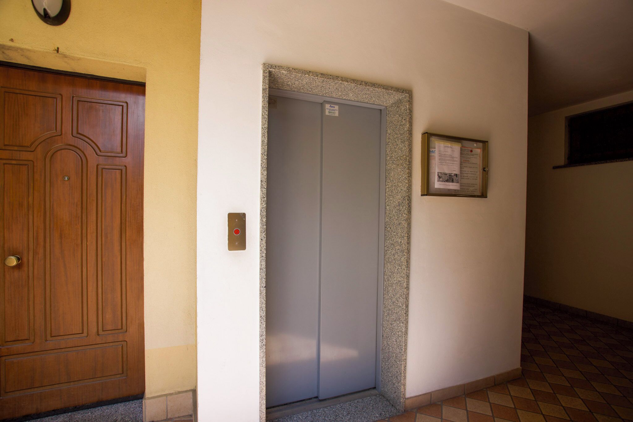 A hallway with a wooden door and an elevator.