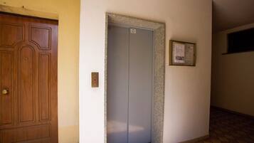 A hallway with a wooden door and an elevator.