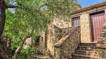 A stone staircase leading to a rustic building with a wooden door and window.