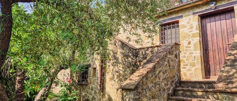 A stone staircase leading to a rustic building with a wooden door and window.