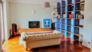 A modern living room with a sofa, television, bookshelf, and a pendant light. - Affittacamere Profumo Campestre (Frigento)