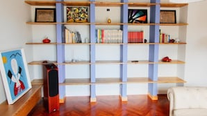 A room with a wooden bookshelf, a red speaker, and a framed artwork on the left. - Affittacamere Profumo Campestre (Frigento)