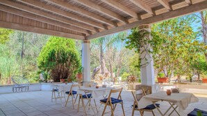 An outdoor patio area with tables and chairs, surrounded by trees and plants.