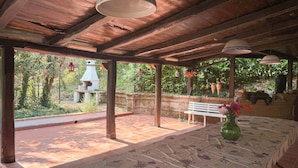 A covered patio with a table set for dining, a bench, and hanging lanterns. - La Masseria (Montemiletto)