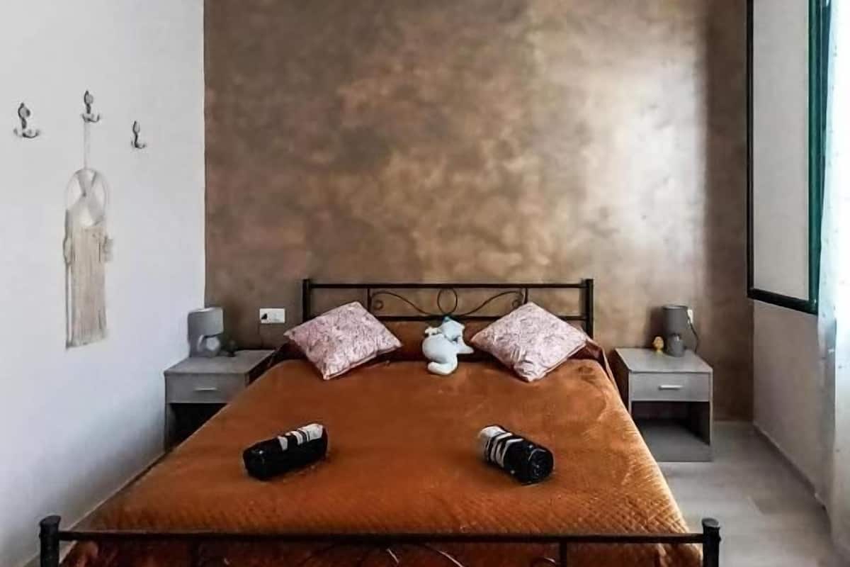 A modern bedroom with a large bed, two nightstands, and a wall-mounted shelf.