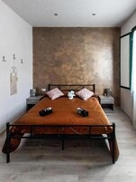 A modern bedroom with a large bed, two nightstands, and a wall-mounted shelf.