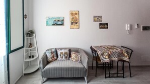 A compact living space with a sofa, a dining table, and wall decorations. - Casa Al Porticciolo (Trapani)